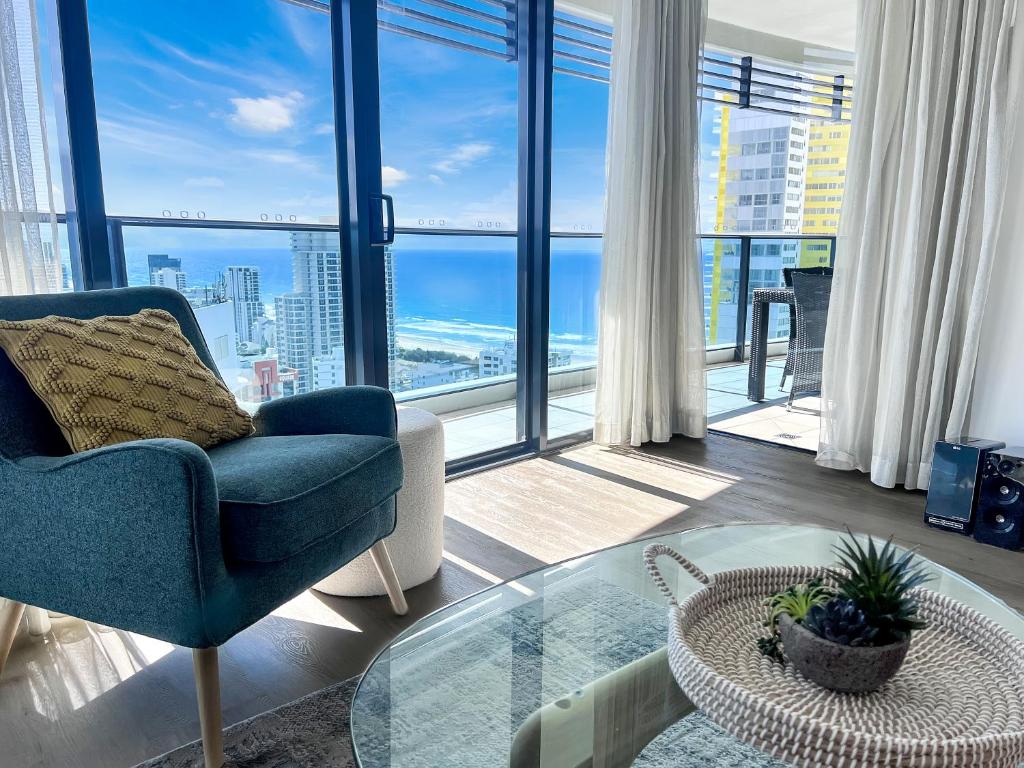 a living room with a blue chair and a glass table at Oracle 28th floor Tower 2 Ocean views! - GC Getaways in Gold Coast