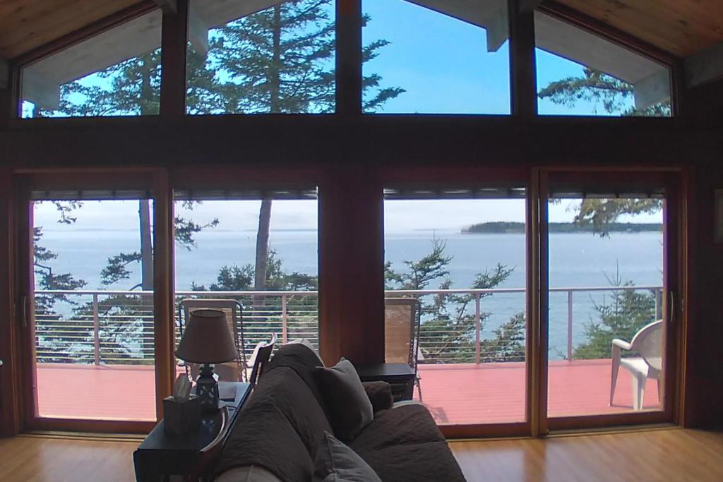 ein Wohnzimmer mit einem Sofa und großen Fenstern in der Unterkunft Reed Shore Cottage in Bass Harbor