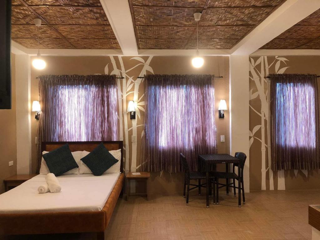 a bedroom with a bed and a table and two windows at Anahaw Seaside Inn in Bantayan Island