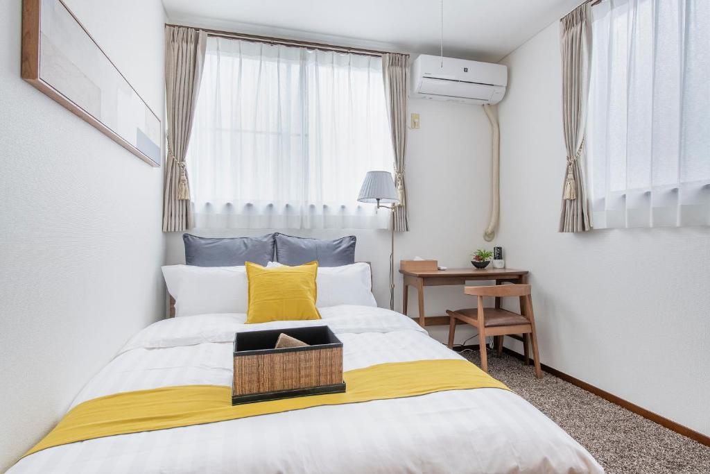 a bedroom with a bed with a yellow and white blanket at Hatagaya House in Tokyo
