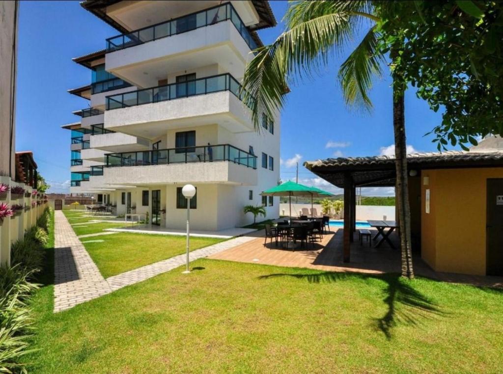 a large white building with a patio and a table at Porto de Galinhas - Apartamento Flat Sea Residence 304 in Porto De Galinhas