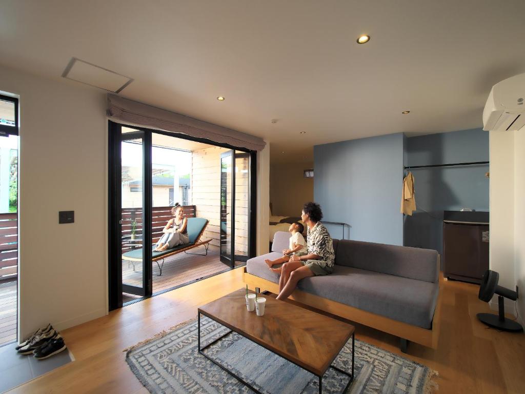 a man and a child sitting on a couch in a living room at ＨＯＴＥＬ ＬＯＣＡＬ ＢＡＳＥ＜宮古島＞ in Miyako Island