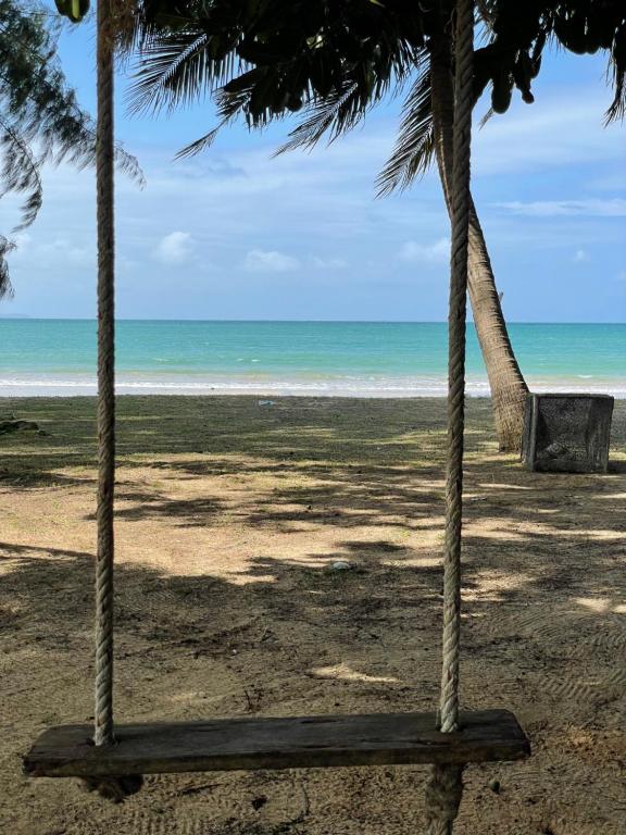 a beach with two palm trees and the ocean at BaanYaiGuesthouse in Ko Mak