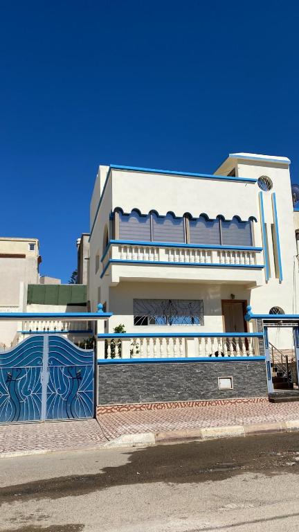 uma casa branca com uma cerca azul e um portão em Apartamento moulay bouslham em Riah