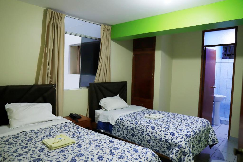Habitación de hotel con 2 camas y espejo en HOTEL ABANCAY, en Abancay
