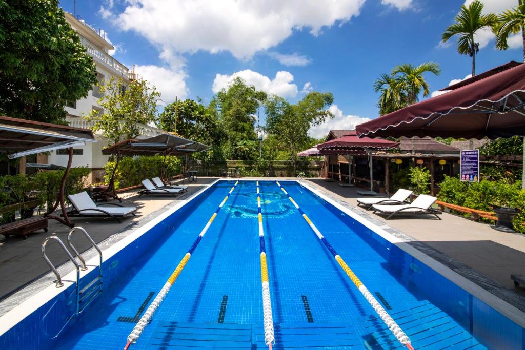 uma grande piscina com espreguiçadeiras e guarda-sóis em Citrus Village Villa Hoi An em Hoi An