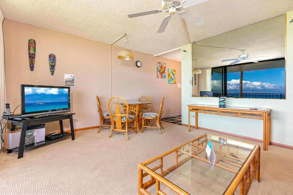 een woonkamer met een televisie en een tafel en stoelen bij Paki Maui #103 condo in Kahana