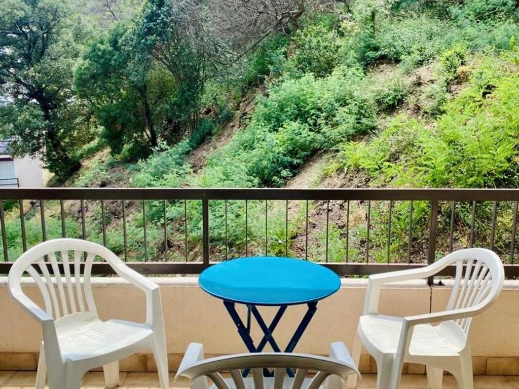 une table et deux chaises sur un balcon avec vue dans l'établissement Studio ensoleillé avec balcon et parking - WiFi inclus - Centre-ville Amélie-les-Bains - FR-1-703-164, à Amélie-les-Bains-Palalda