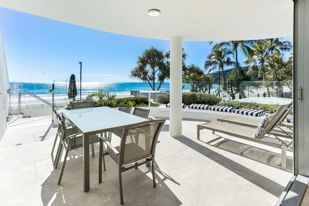 a patio with a table and chairs and the ocean at Beachfront luxury, Hastings Street in Noosa Heads