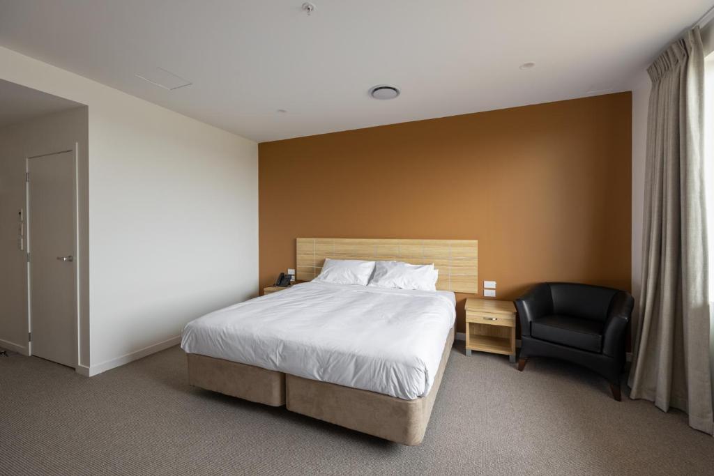 a hotel room with a bed and a chair at Manha Hotel Auckland Airport in Auckland