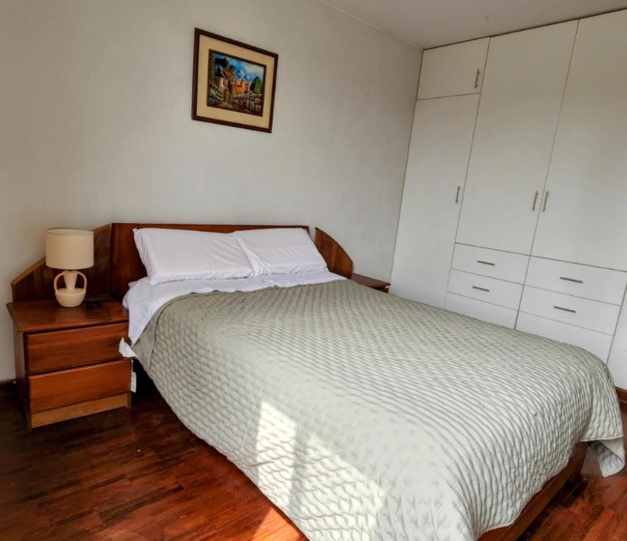 a bedroom with a bed and a night stand with a lamp at Casita Cultura in Lima