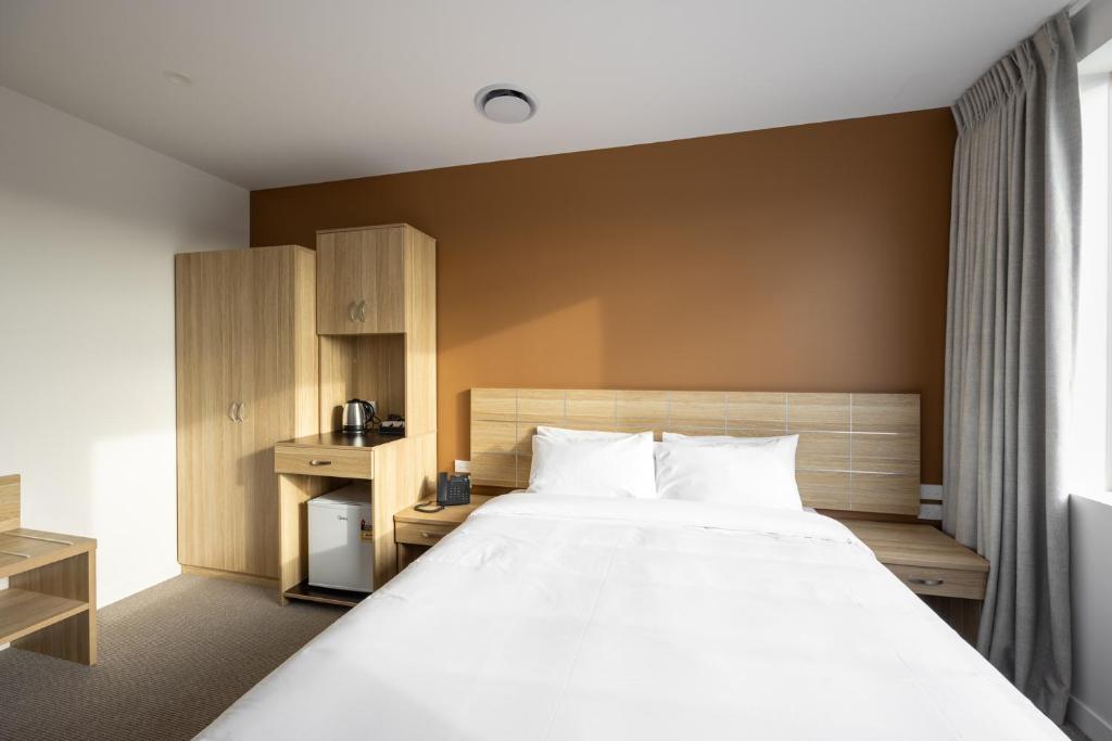 a bedroom with a large white bed and a window at Manha Hotel Auckland Airport in Auckland