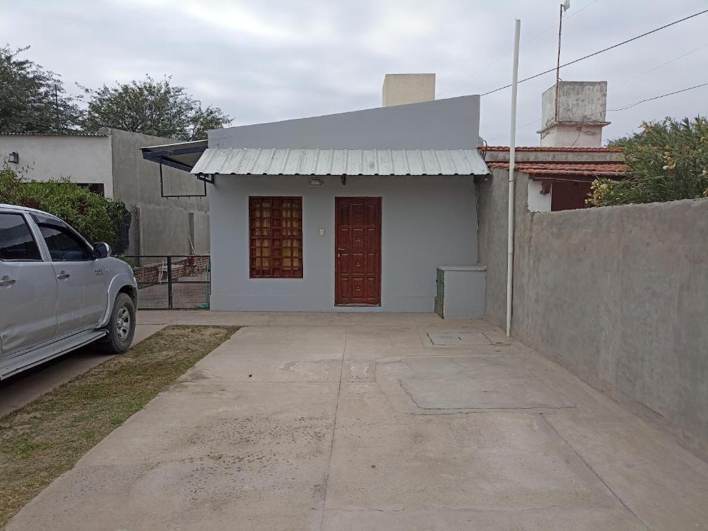 een klein wit huis met een auto ervoor geparkeerd bij Atardecer Santiagueño in Fernández
