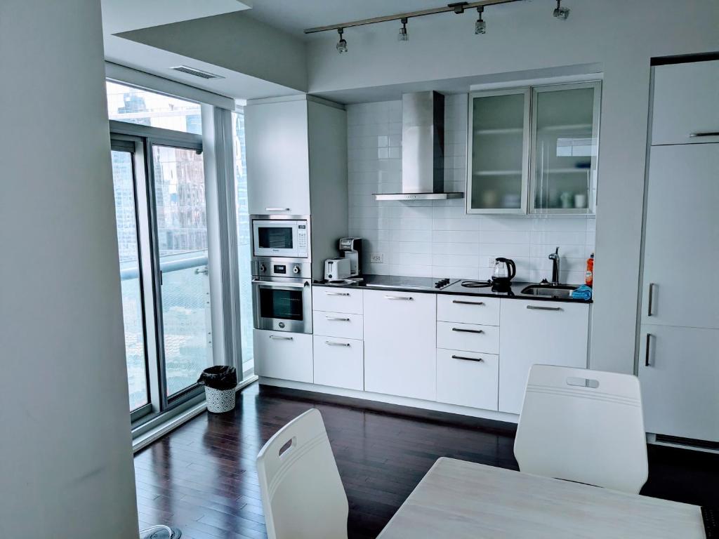 a kitchen with white cabinets and a table and chairs at ICE Condominiums in Toronto