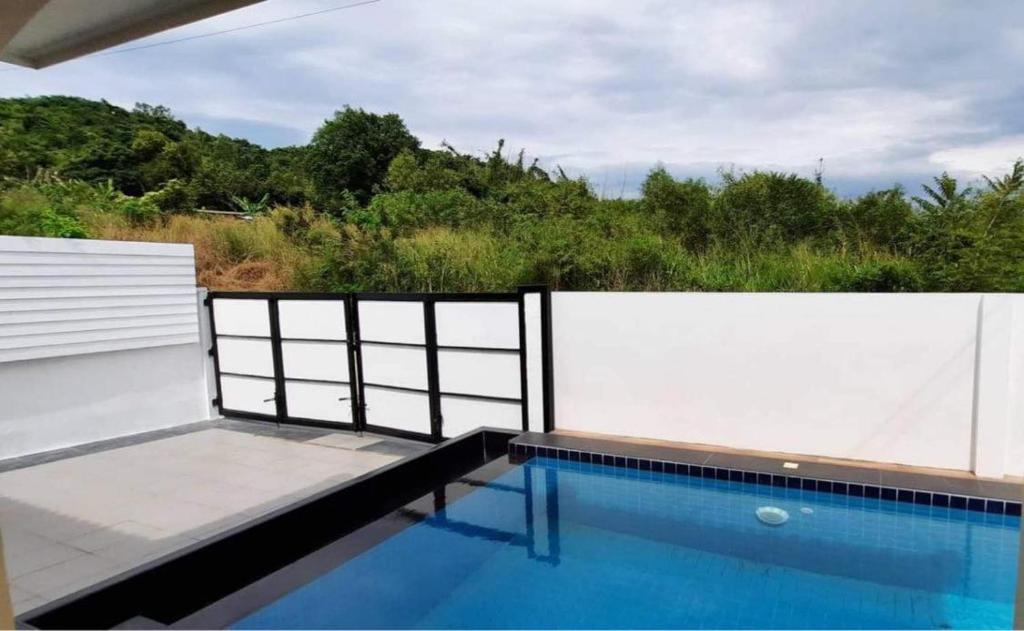 einen Pool mit einem weißen Zaun neben einer weißen Wand in der Unterkunft Pool Villa Sattahip White House in Ban Tao Than