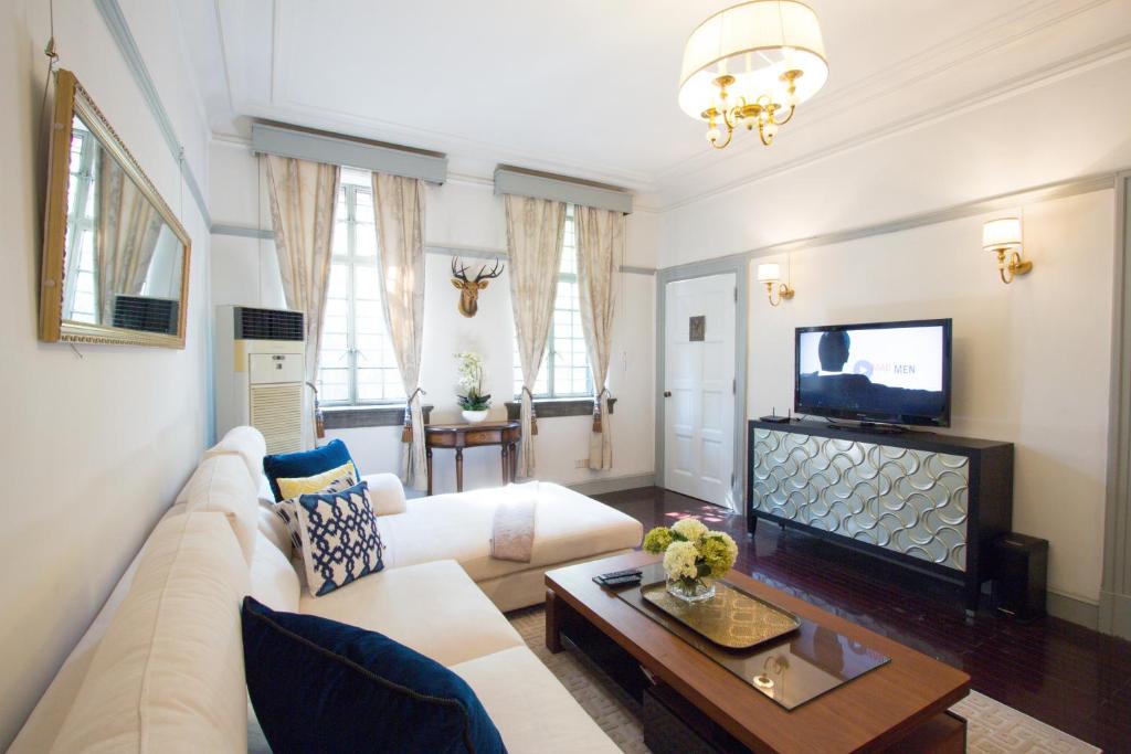 a living room with a white couch and a tv at Classic Victorian Presidential Suite West Nanjing Rd in Shanghai