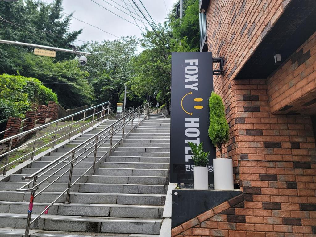 una señal en el lateral de un edificio de ladrillo con escaleras en Foxy Hotel, en Busan