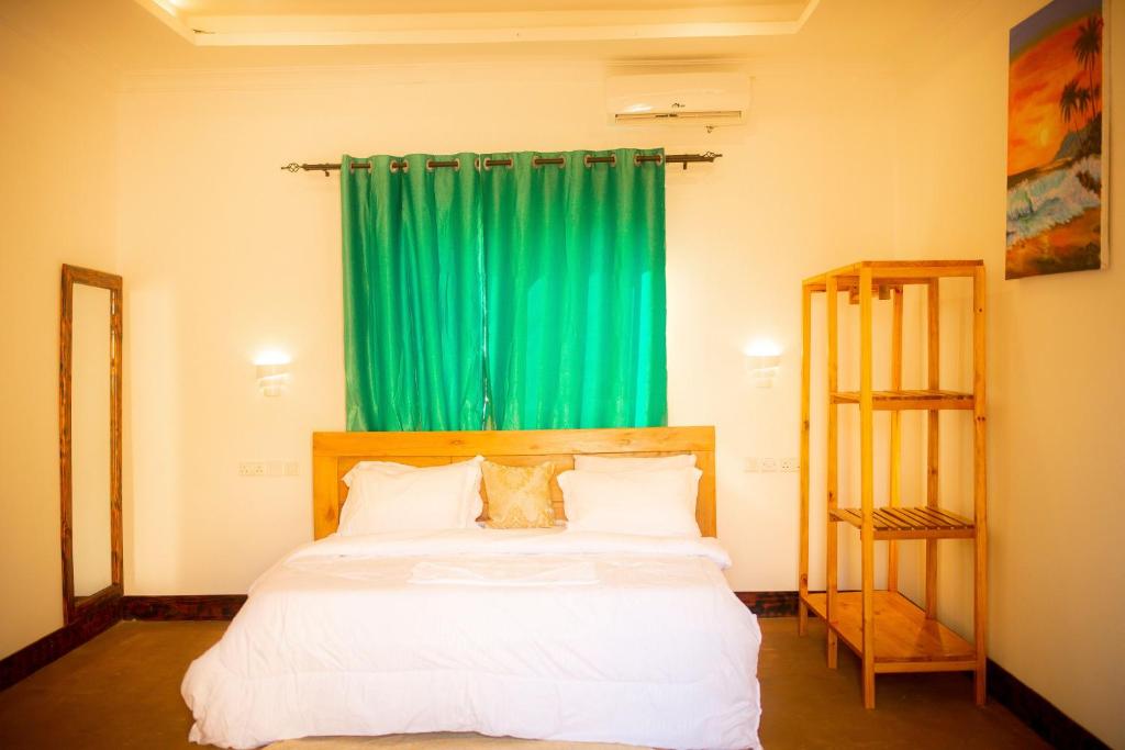 a bedroom with a bed with a green curtain at PALM CULTURAL VILLAGE in Paje