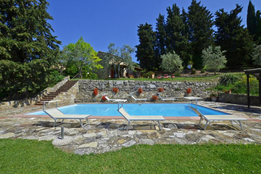einen Pool in einem Garten mit einer Steinmauer in der Unterkunft La Badia - Happy Rentals in Tavarnelle in Val di Pesa