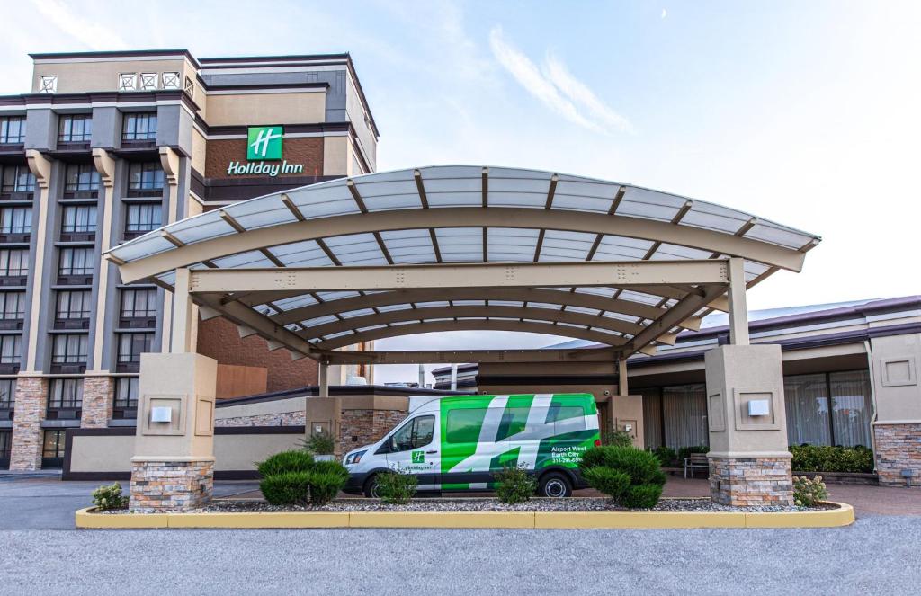 une camionnette verte garée sous un auvent devant un bâtiment dans l'établissement Holiday Inn St. Louis Airport West Earth City, an IHG Hotel, à Earth City