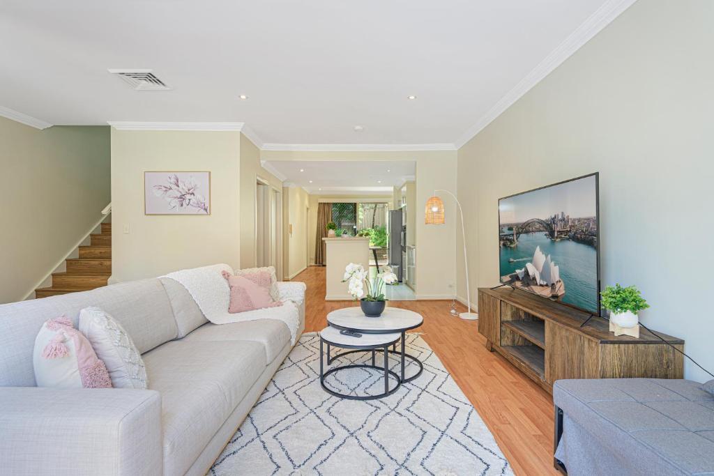a living room with a couch and a tv at Marsfield New Modern Townhouse in Sydney