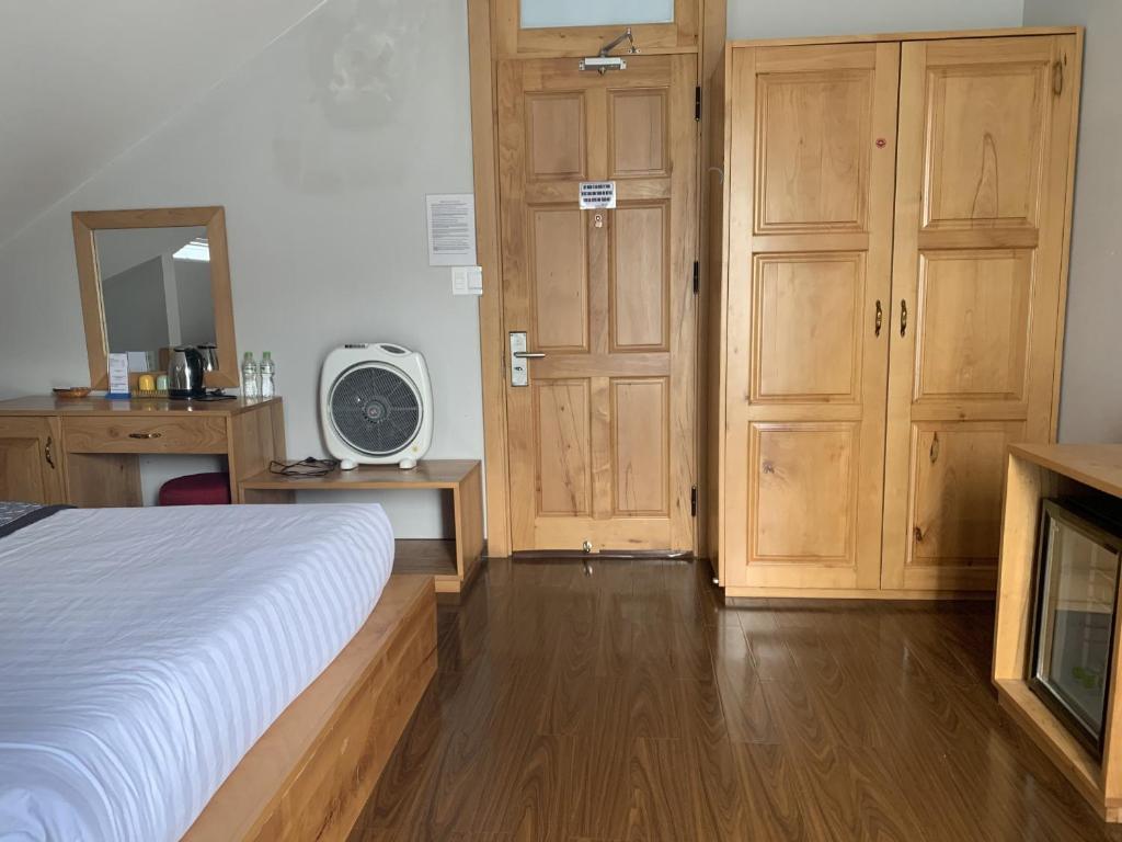 a bedroom with a bed and wooden cabinets and a tv at Dalat Wind Hotel in Da Lat