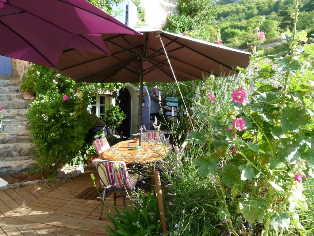 a table and chairs under an umbrella in a garden at chambre campagnarde in Bargème