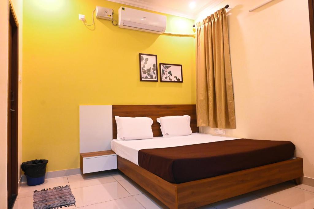 a bedroom with a bed and a yellow wall at KK SERVICE APARTMENTS in Vellore