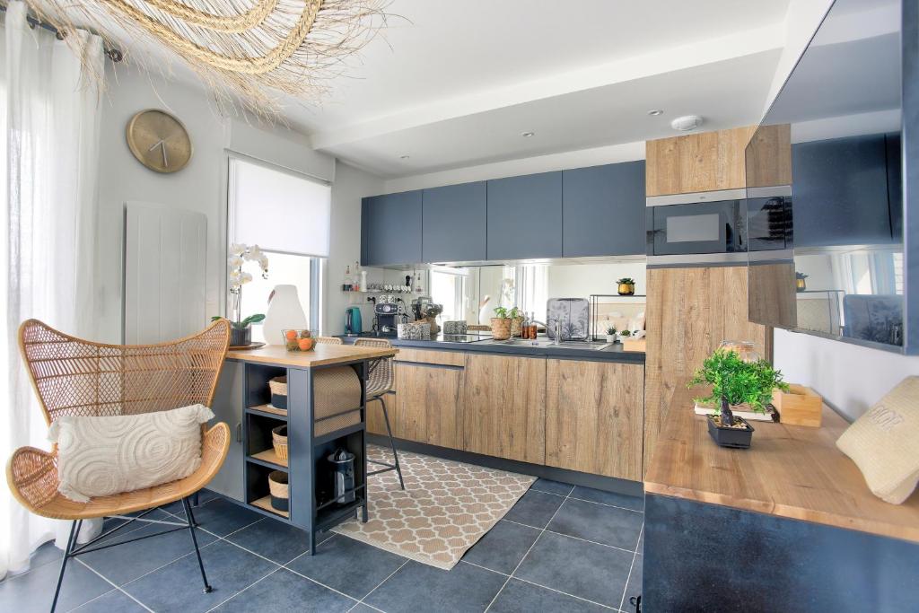 une cuisine avec des placards bleus et une table avec une chaise dans l'établissement Bella Cruz - Charmant appt à Dinard, à Dinard