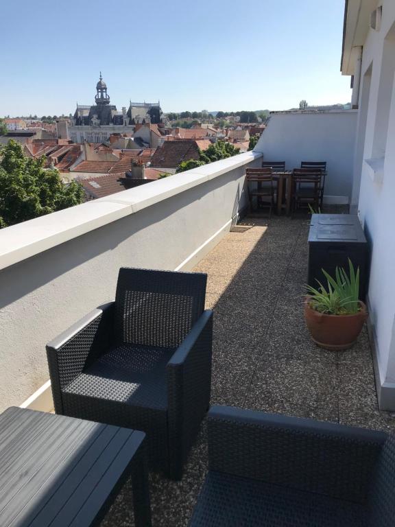 a balcony with chairs and tables on a roof at Appartement avec vue panoramique in Vichy