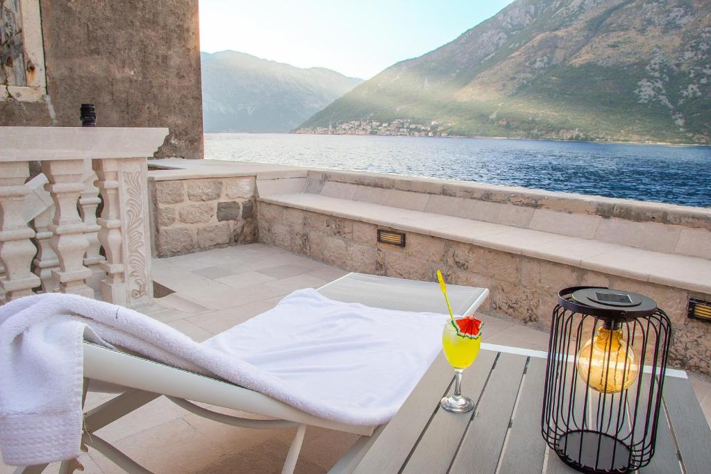 a table with a drink on a balcony with a view of the water at Pallazo Uniqato seafront in Kotor