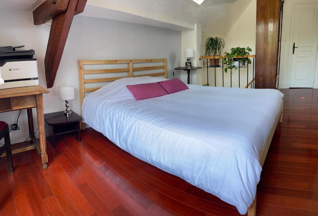 a bedroom with a large white bed and a wooden floor at Chez Hélène, calme et verdure au centre historique in Vincennes