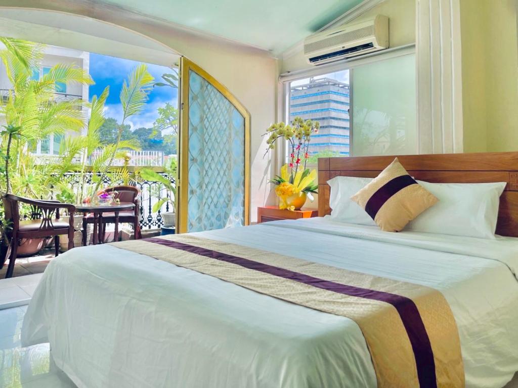 ein Schlafzimmer mit einem großen Bett und einem Balkon in der Unterkunft Hải Nam Hotel (Sài Gòn) in Ho-Chi-Minh-Stadt