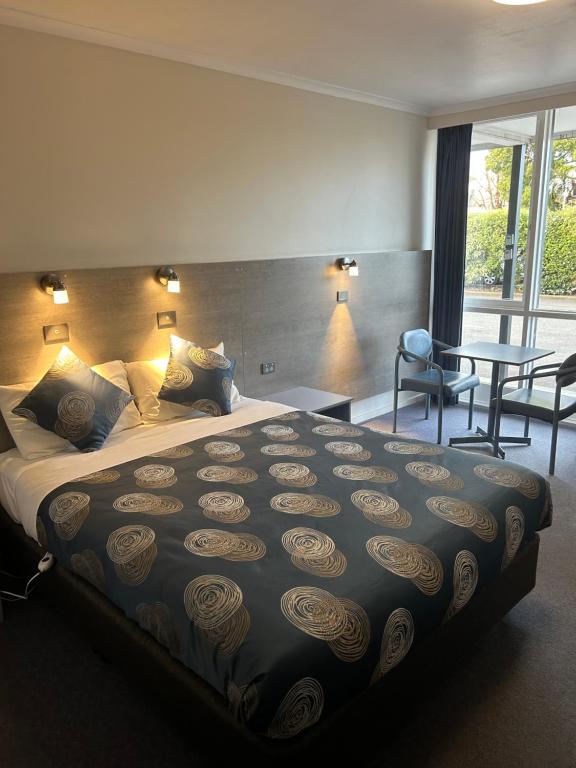 a hotel room with a large bed and a table at Colac Central Motel in Colac