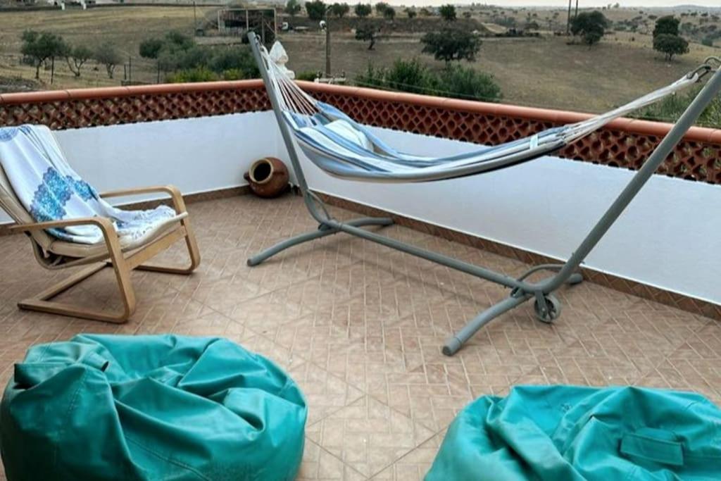 a hammock and a chair on a balcony at Casa dos AVÓS in Santana de Cambas