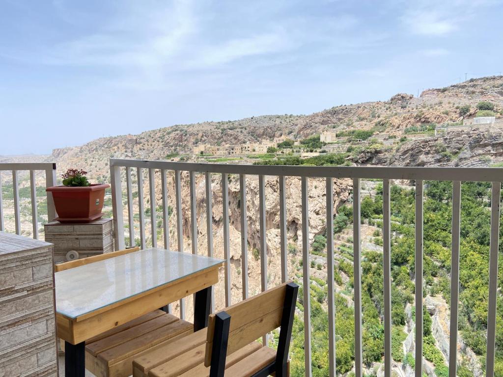 una mesa y un banco en un balcón con vistas en استراحة الشرف ALSHARAF, en Al ‘Aqar