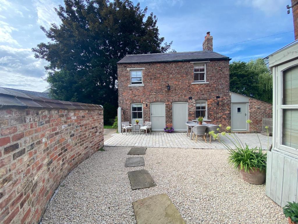 a brick house with a patio in front of it at Grooms Cottage next to Sheriff Hutton Castle in Sheriff Hutton