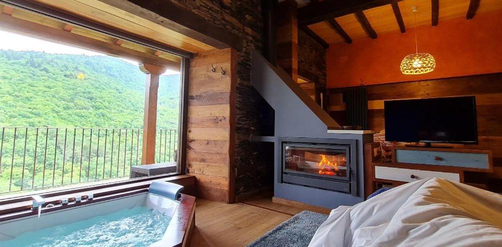een kamer met een hot tub en een open haard bij Apartamentos Rurales El Bosque de las Viñas in Boal