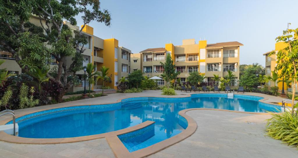 アンジュナにあるHotel Reemz Beach Heaven , Anjunaの一部のアパートメントビルの前にスイミングプールがあります。