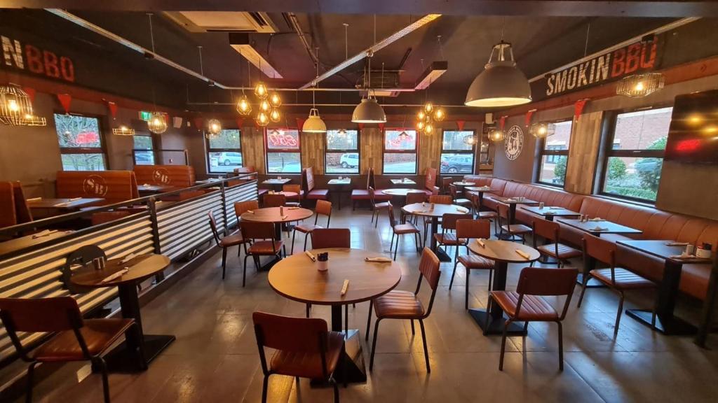 un ristorante con tavoli e sedie in legno e finestre di Travelodge Dublin Airport North 'Swords' a Swords