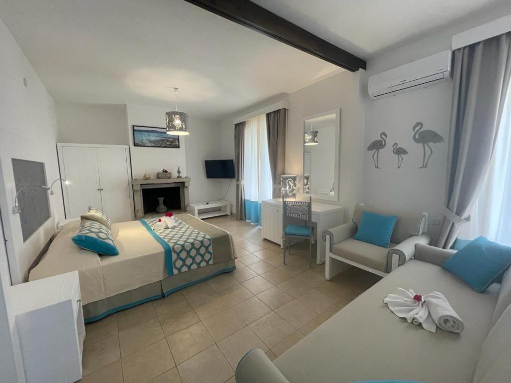 a bedroom with a bed and a living room with a couch at San Raffaele Guest House in Villasimius