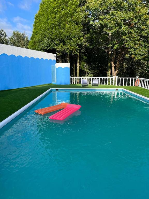 a large swimming pool with two red chairs in the water at QUINTA DONA MANUELA in Formariz
