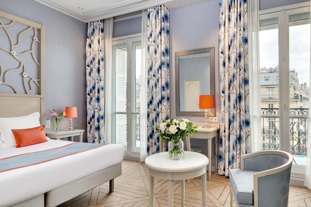 a bedroom with a bed and a table and a chair at Splendid Etoile in Paris