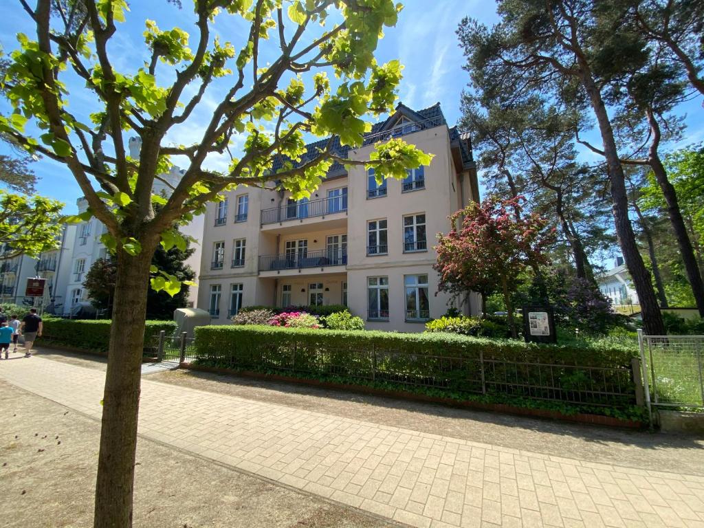 a large white building with a hedge in front of it at Haus Sabine - Ferienwohnung Mine in Ahlbeck