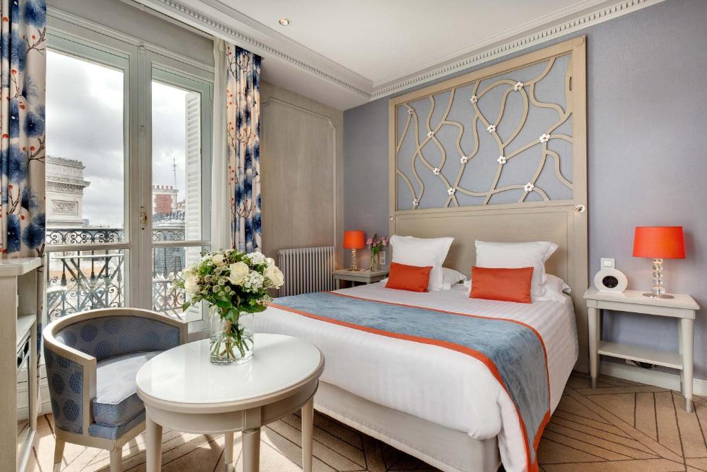 a bedroom with a bed and a table and a window at Splendid Etoile in Paris