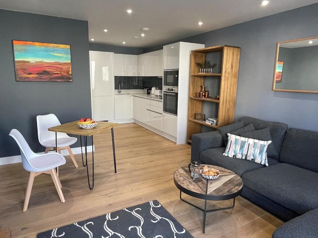 a living room with a couch and a table and a kitchen at Harbourside Hideaway - Superb Flat with Terrace in Bristol