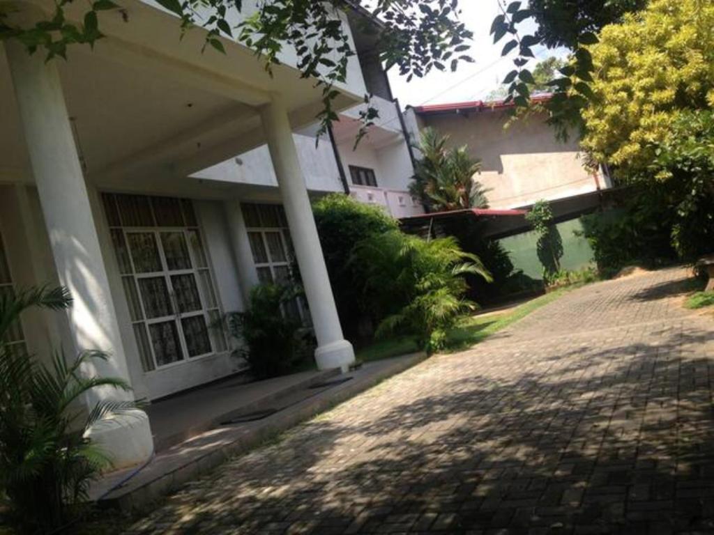 a white house with a porch and a driveway at Vegan Stay by The Vegan Kitchen by Sulo in Boralesgamuwa