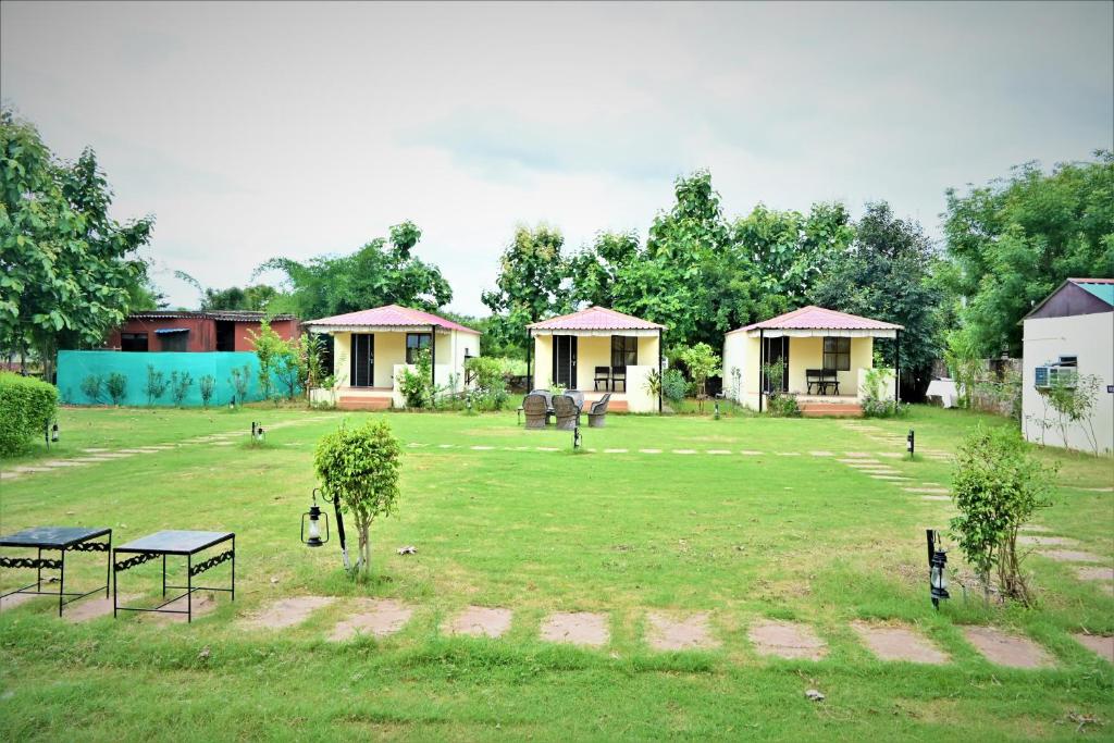 einen großen Hof mit Häusern, Bäumen und Gras in der Unterkunft Ranthambore Jungle Home in Khilchīpur
