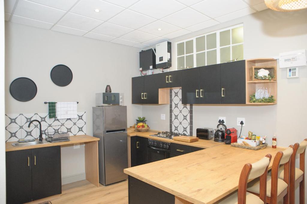 a kitchen with black cabinets and a wooden table at Royal Pearl, Insta-worthy APT in Paarl