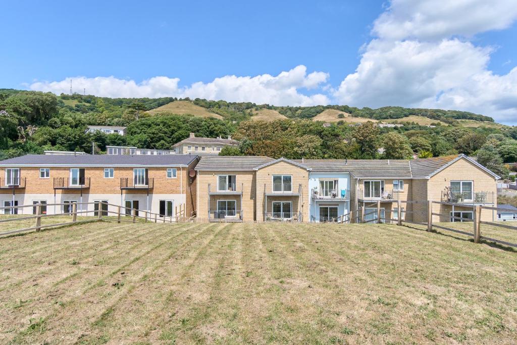 um campo vazio em frente a uma casa grande em Stunning 3 Bed Apt With Countryside Views & Parking - Ideal For Families, Groups & Business Stays - Close To Ventnor, Shanklin & Sandown em Ventnor